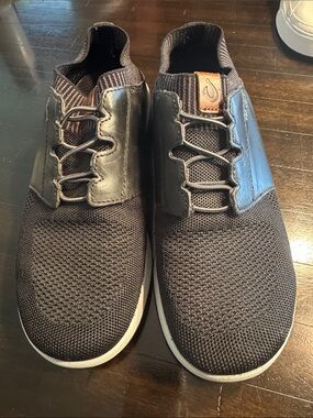 OluKai Moku-pai Men’s Knit Slip-On Sneakers in Black with black leather accent.